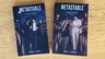 Paperback copies of Metastable: Book One of Two and Book Two of Two arranged together on a wooden surface.